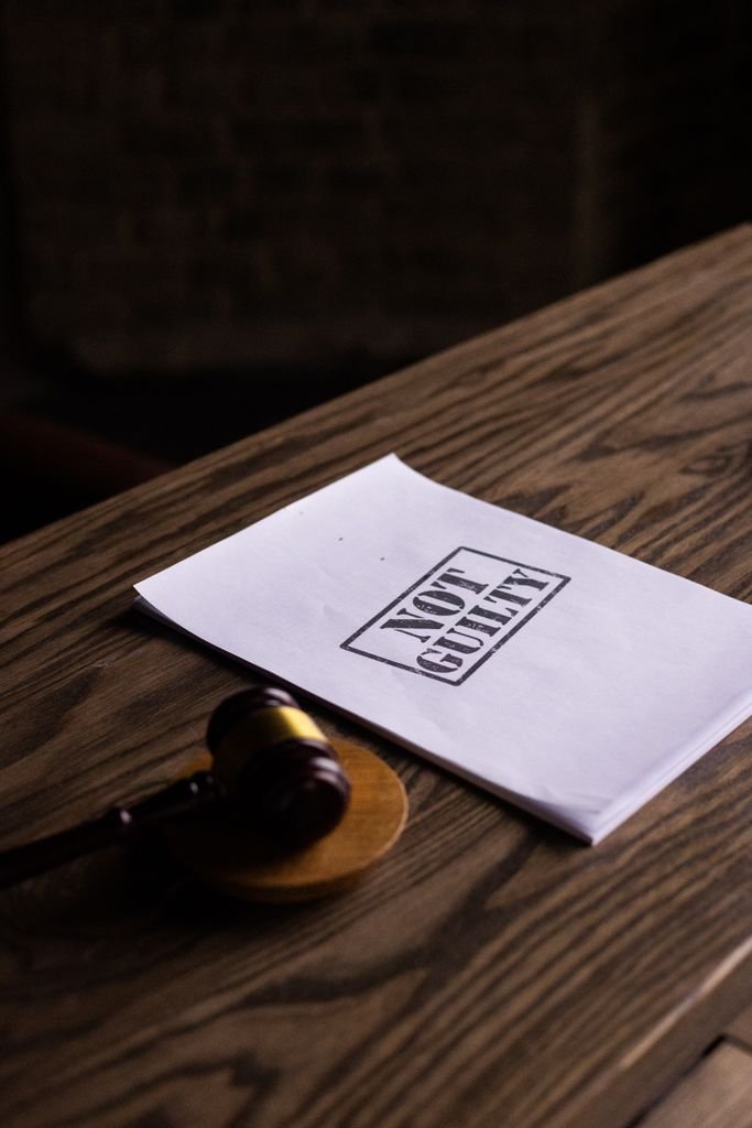 A legal gavel next to a 'Not Guilty' document on a wooden table, symbolizing justice.